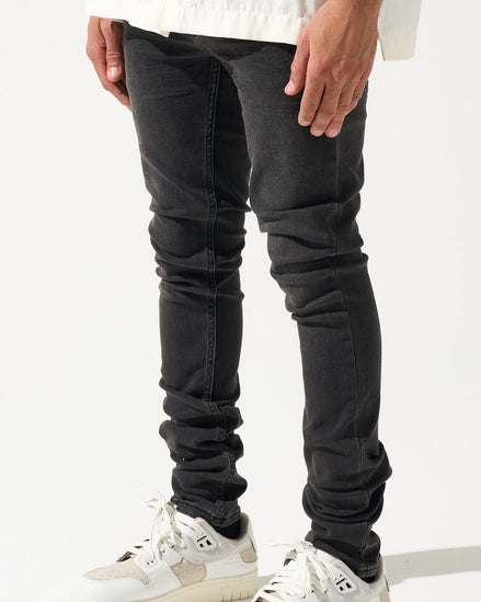 Person wearing black jeans and white sneakers on a white background
