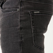 Close-up of black jeans with a visible brand label on a white background
