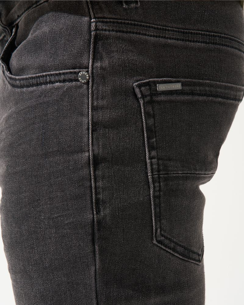 Close-up of black jeans with a visible brand label on a white background