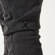 Close-up of dark gray pants with a brand logo on a white background