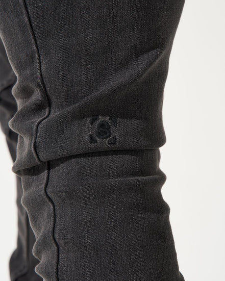 Close-up of dark gray pants with a brand logo on a white background