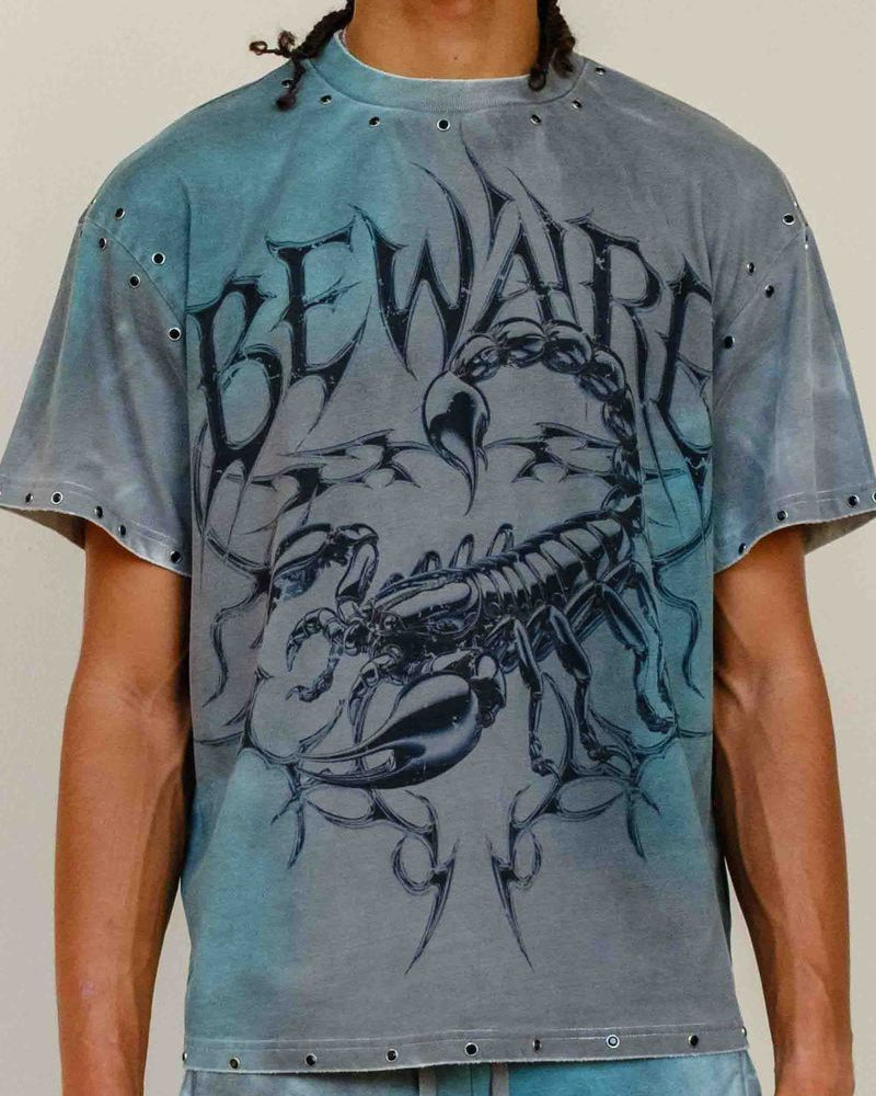 Person wearing a distressed t-shirt with a scorpion graphic and 'Beware' text.
