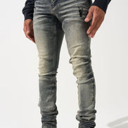 Person wearing distressed gray jeans and black sneakers on a white background