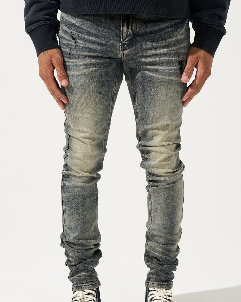 Person wearing gray distressed jeans and black high-top sneakers on a white background