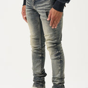 Person wearing distressed gray jeans and black sneakers with red accents on a white background