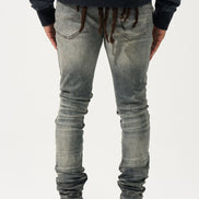 Person wearing gray distressed jeans and black shoes with red accents on a white background