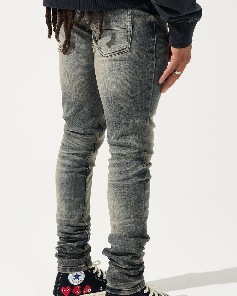 Person wearing gray jeans and black sneakers with red heart designs on a white background