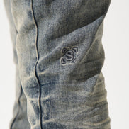 Close-up of a distressed denim jeans with a brand logo on a white background