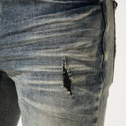 Close-up of a distressed denim jeans with a white background