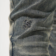 Close-up of a gray denim fabric with a brand logo on a white background
