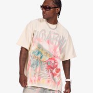 A man modeling an oversized cream-colored graphic t-shirt with a vibrant pink, blue, and yellow abstract print and the word 'SUGARHORN' across the chest, paired with light-wash jeans and sunglasses, against a plain light gray background.