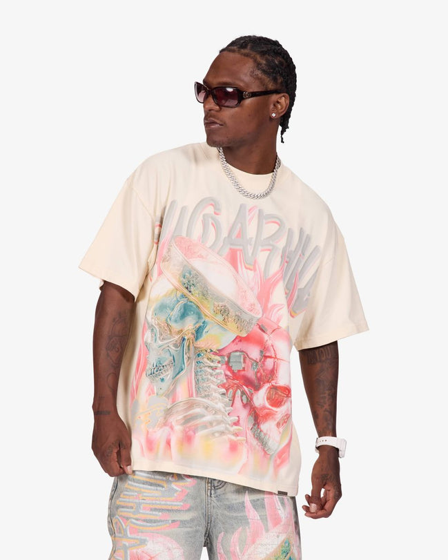 A man modeling an oversized cream-colored graphic t-shirt with a vibrant pink, blue, and yellow abstract print and the word 'SUGARHORN' across the chest, paired with light-wash jeans and sunglasses, against a plain light gray background.