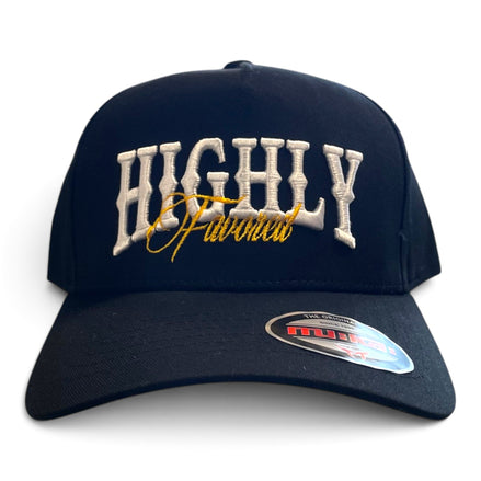 A black baseball cap featuring 'HIGHLY Favored' embroidered on the front in white and gold, with a visible Migs brand sticker on the brim.