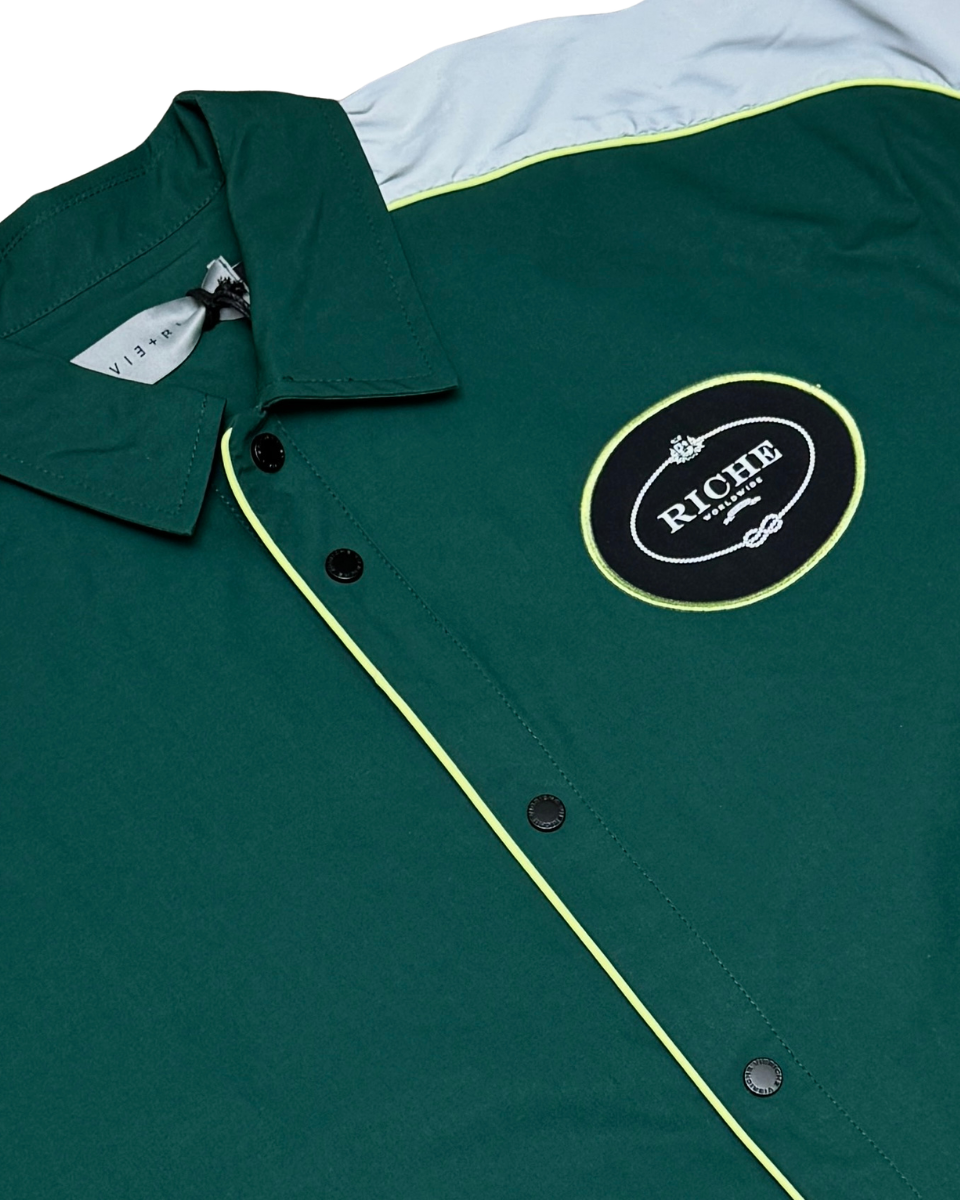 Green jacket with a logo patch on a white background