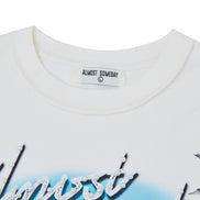 White t-shirt with 'Almost Someday' label and floral design on a white background