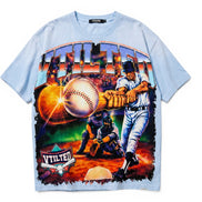 A light blue short-sleeve t-shirt with a large, colorful graphic print on the front featuring a baseball player, a catcher, a baseball, and the word 'VTILTED' in stylized lettering.
