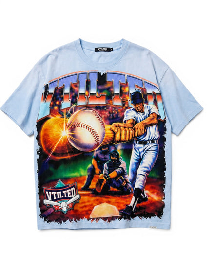 A light blue short-sleeve t-shirt with a large, colorful graphic print on the front featuring a baseball player, a catcher, a baseball, and the word 'VTILTED' in stylized lettering.