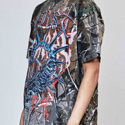Person wearing a graphic t-shirt with a camouflage pattern and colorful design on a plain background