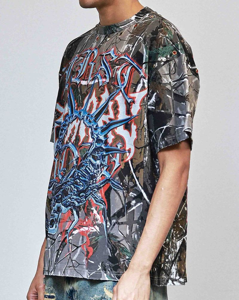 Person wearing a graphic t-shirt with a camouflage pattern and colorful design on a plain background