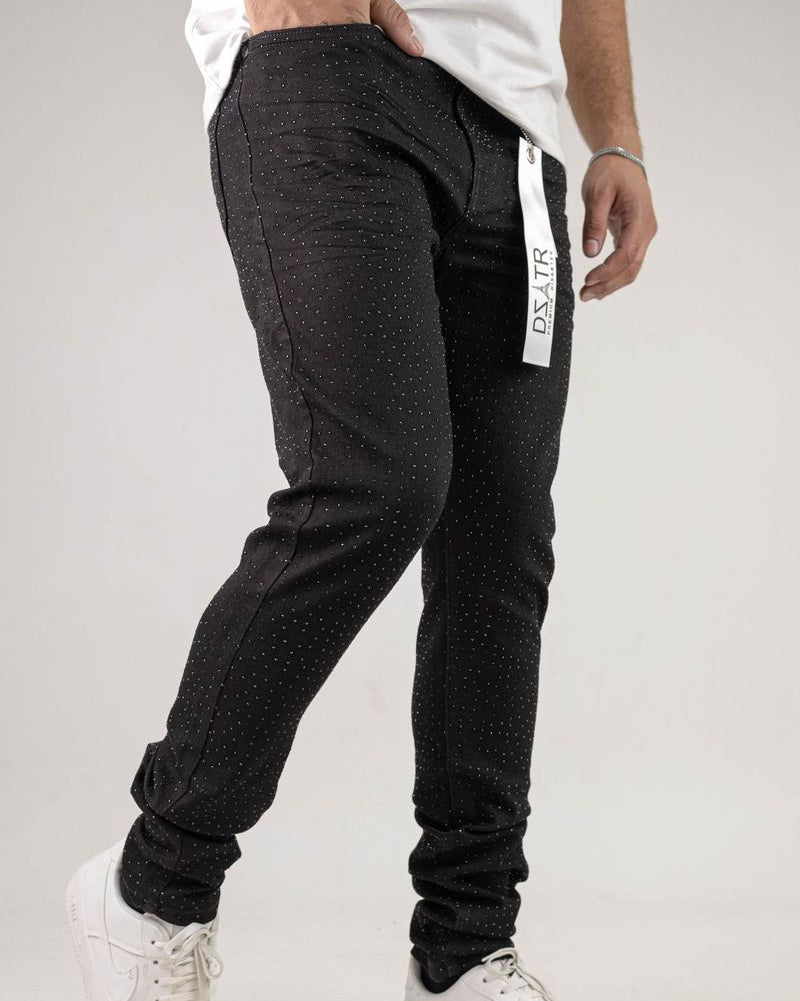 Person wearing black jogger pants with a visible brand logo on a light gray background