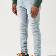 Person wearing light blue jeans and brown shoes with colorful laces on a white background