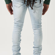 Person wearing light blue jeans and green sweatshirt with a plain background