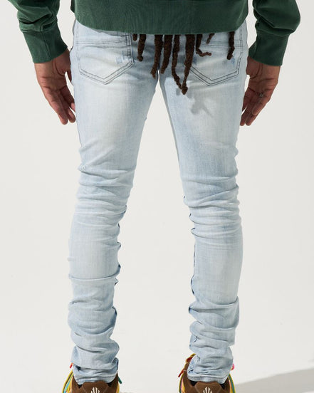 Person wearing light blue jeans and green sweatshirt with a plain background
