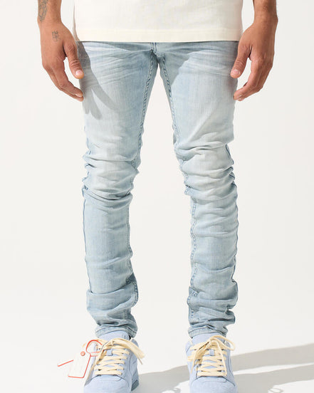 Person wearing light blue jeans and white sneakers on a white background