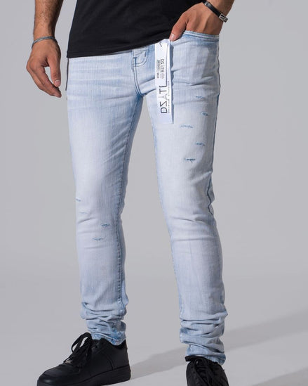 Light wash blue slim-fit jeans with distressed details and a vertical brand tag on the front pocket, shown on a model wearing a black t-shirt and black sneakers against a gray studio background.