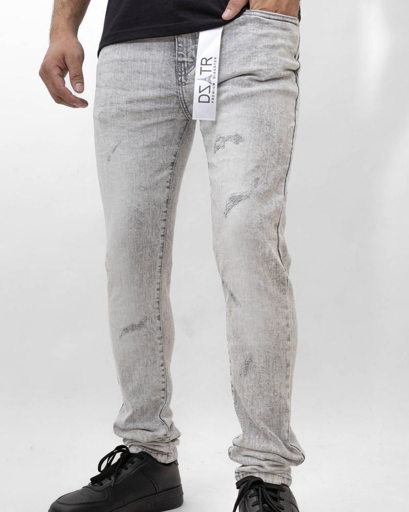 Person wearing light gray distressed jeans with a black shirt and black shoes on a white background
