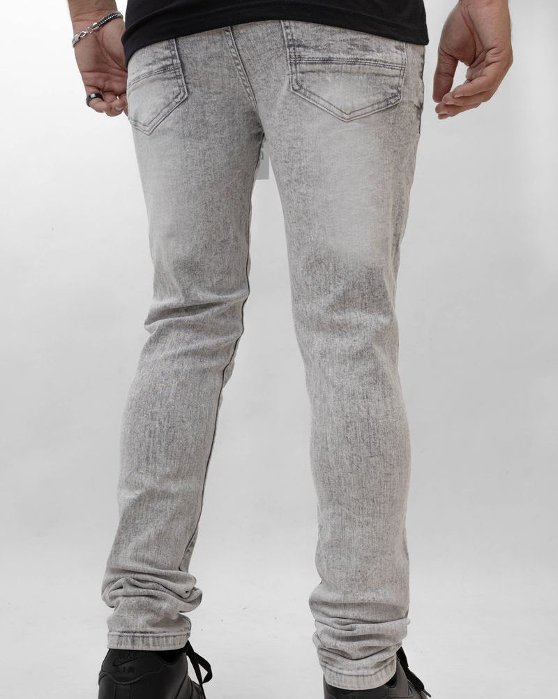 Person wearing gray jeans and black shoes on a white background