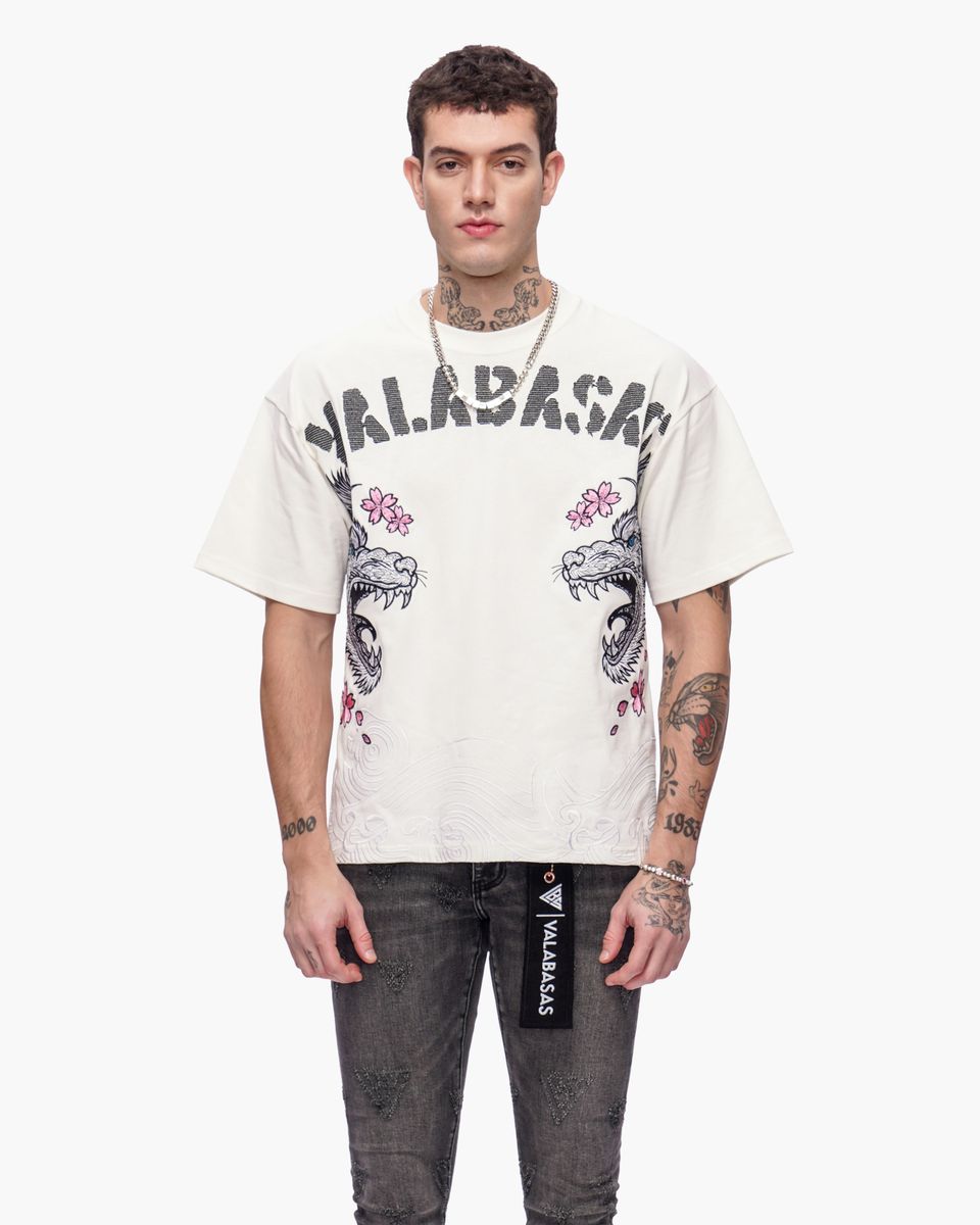 Man wearing a white t-shirt with graphic designs and text, standing against a white background