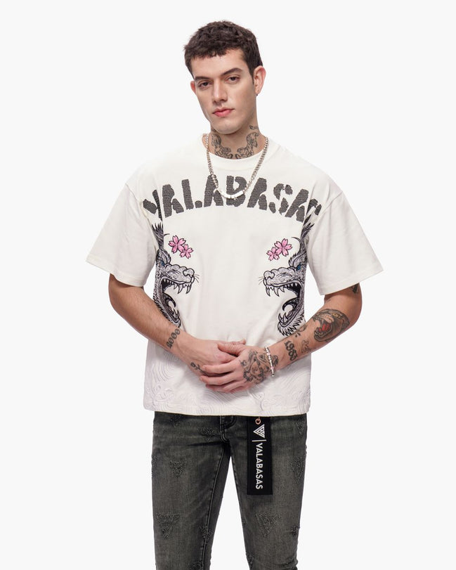 Person wearing a white t-shirt with graphic designs and text, standing against a white background