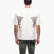 Person wearing a white t-shirt with black and red designs on the back, standing against a white background.