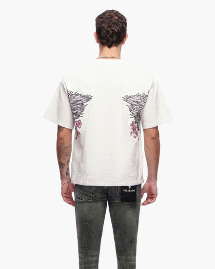 Person wearing a white t-shirt with black and red designs on the back, standing against a white background.