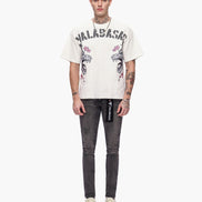 Person wearing a white t-shirt with graphics and text, paired with dark jeans on a white background