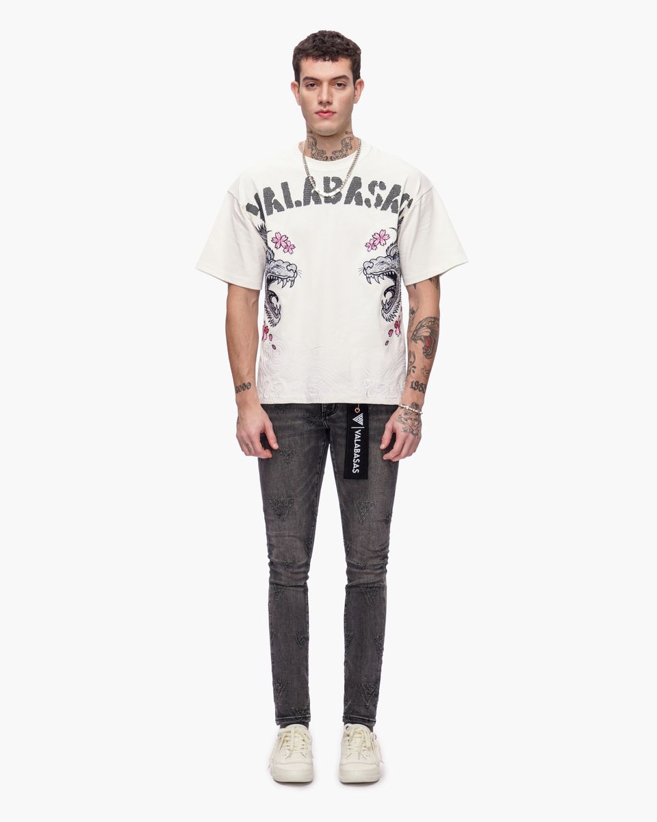 Person wearing a white t-shirt with graphics and text, paired with dark jeans on a white background