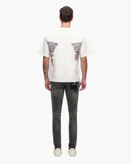 Person wearing a white t-shirt with a graphic design and dark jeans on a white background
