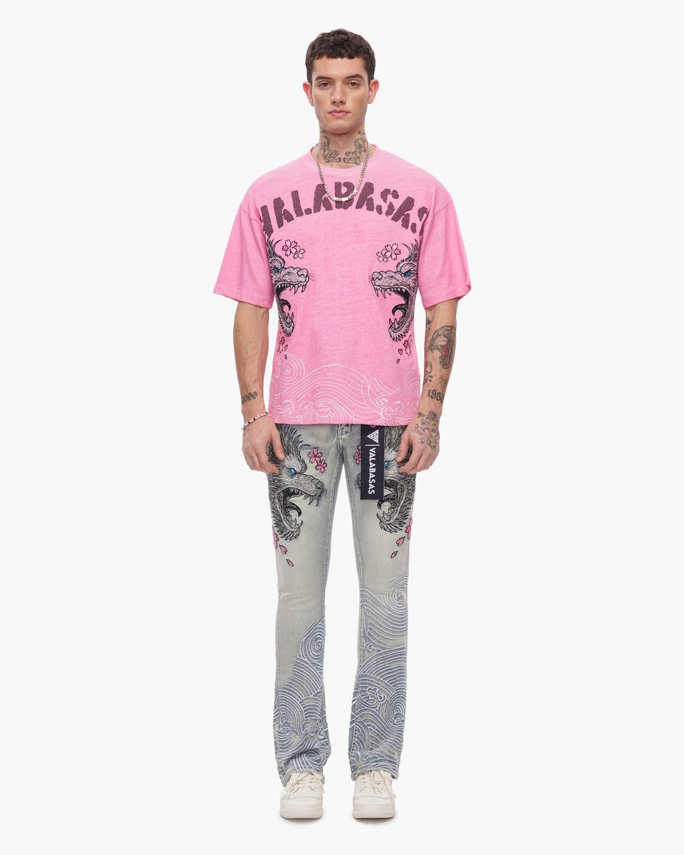 Person wearing a pink t-shirt with graphic design and patterned pants on a white background