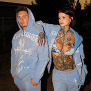 Two people in matching blue outfits standing outdoors at dusk.