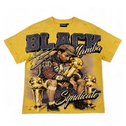 A yellow graphic t-shirt featuring a stylized illustration of Tupac Shakur sitting with four gold championship trophies, with the text 'BLACK Mamba' and 'Syndicate' printed on the front.