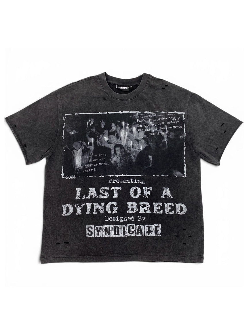 A dark gray washed graphic t-shirt featuring a black-and-white band photo and distressed white text reading 'Presenting Last of a Dying Breed' and 'Designed by Syndicare'.