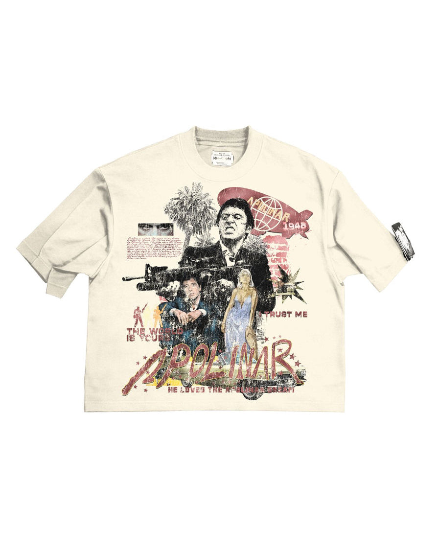 A cream-colored short-sleeve graphic t-shirt featuring a complex collage print with images of John Gotti, a gun, a palm tree, and stylized red and black text, laid flat against a white background.