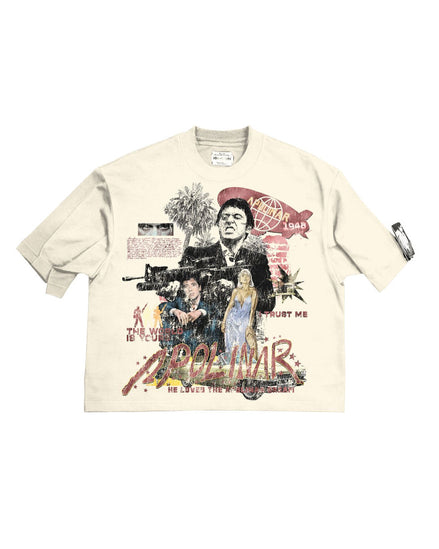 A cream-colored short-sleeve graphic t-shirt featuring a complex collage print with images of John Gotti, a gun, a palm tree, and stylized red and black text, laid flat against a white background.