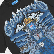 A close-up of a black graphic t-shirt featuring a stylized blue and white illustration of a character in overalls and a yellow hat, with large stylized text across the chest.