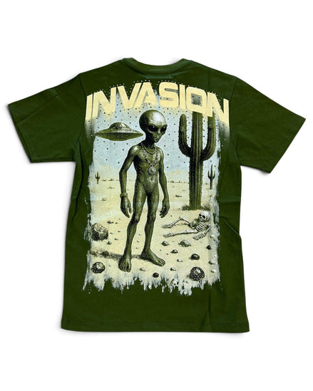 An olive green short-sleeve t-shirt featuring a large graphic print on the front. The graphic depicts a tall alien standing in a desert landscape with a cactus, a UFO, and the word 'INVASION' printed in a distressed cream-colored font above.
