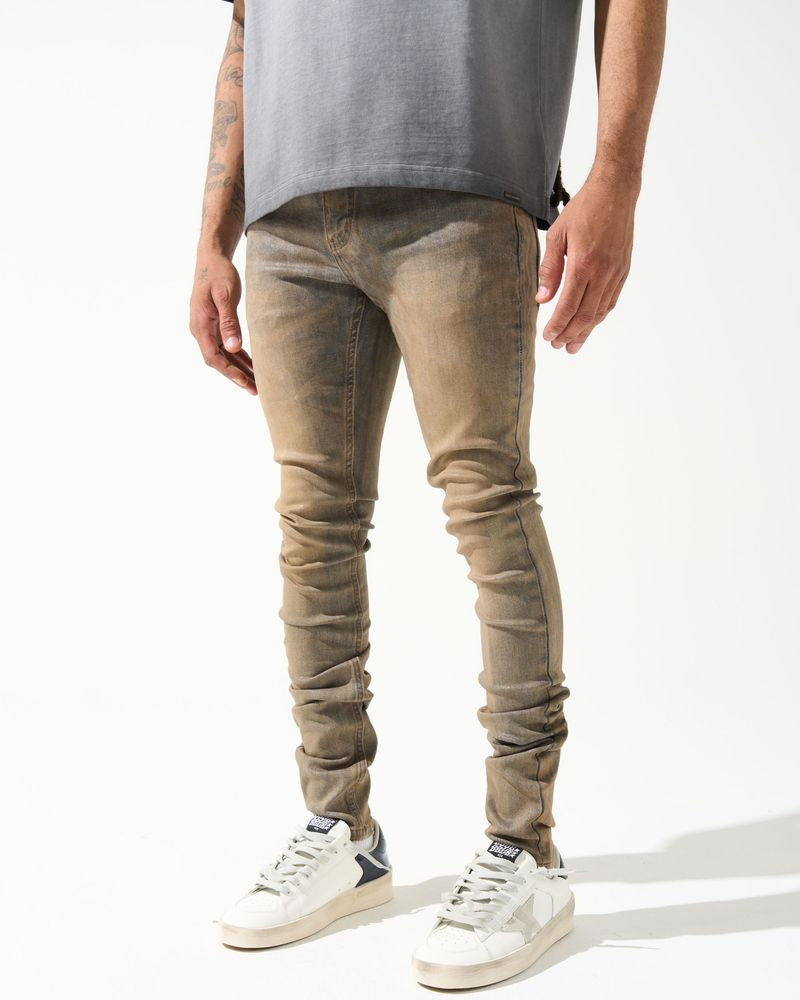 Person wearing beige jeans and white sneakers on a white background