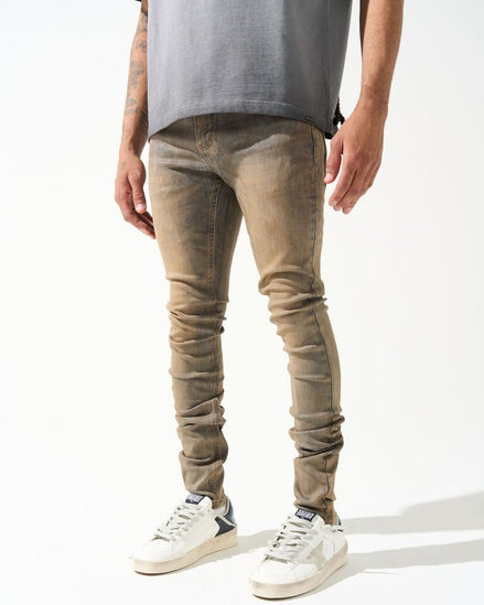 Person wearing beige jeans and white sneakers on a white background