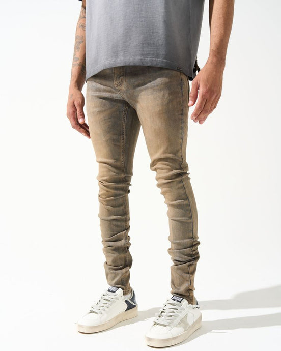Person wearing beige jeans and white sneakers on a white background