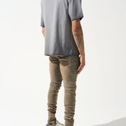 Person wearing a gray t-shirt and beige pants on a white background